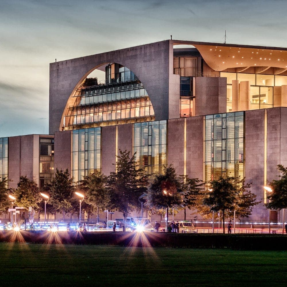 Modern building with large circular window and glass facade at dusk.