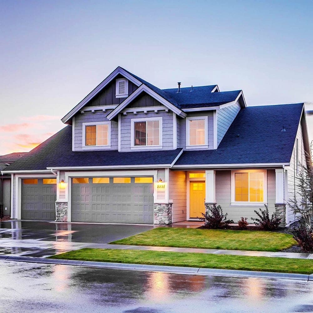 Modern two-story house with gray siding, stone accents, and a three-car garage in Bryan, Texas.