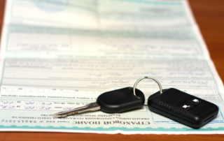 A car key and remote rest on top of a vehicle registration document.