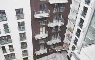 High-rise apartment buildings with glass balconies surround a courtyard with stairs, viewed from an upper floor.