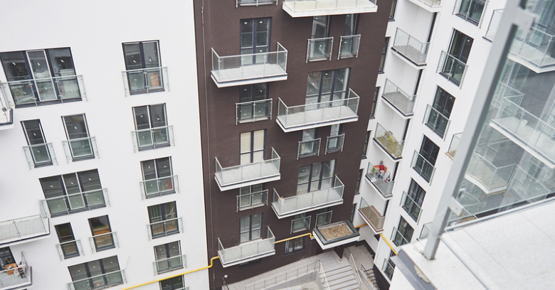 High-rise apartment buildings with glass balconies surround a courtyard with stairs, viewed from an upper floor.