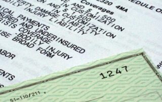 A close-up of a green check partially covering an insurance policy document listing various types of coverage.