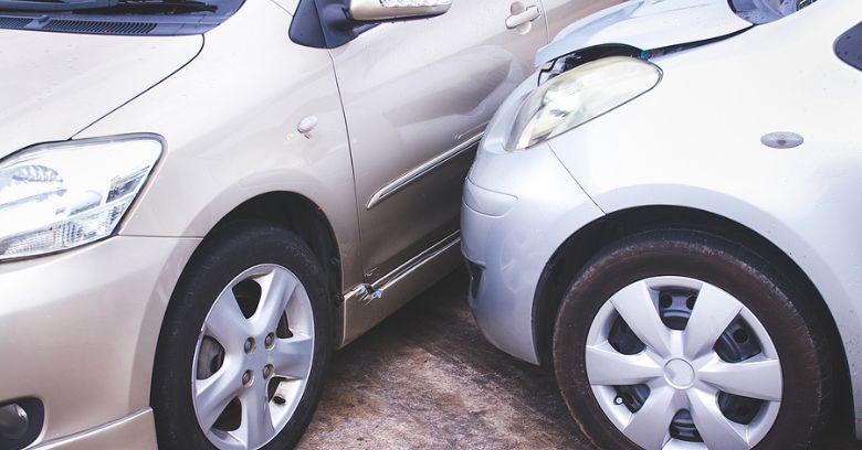 Two silver cars involved in a minor collision, with the front of one car touching the side of the other, showing visible dents and damage.